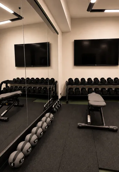 Haltères libres, médecine-balls et bancs d'entraînement dans la salle de fitness de l'hôtel aux murs-miroirs
